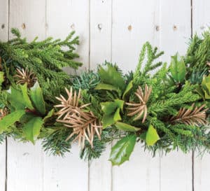 Christmas garland swag made from Southern Living plants greenery, oranges and pine cones set atop a white-washed pallet