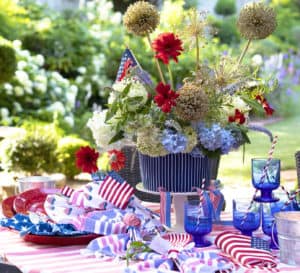 4th of July Tablescape includes a bouquet of Agapanthus and red blooms with a red checked tablecloth, red plates and blue drinkware