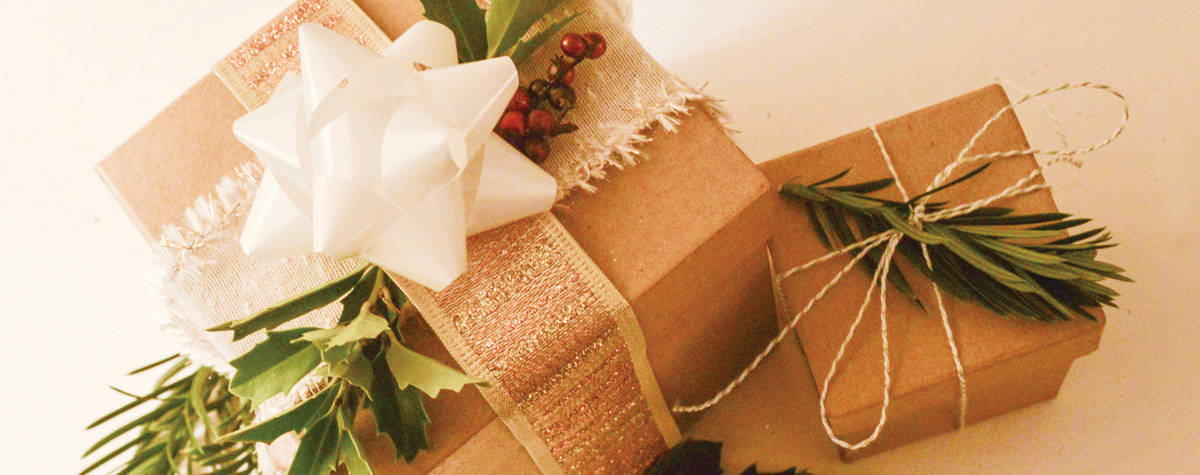 Light brown box presents with golden ribbon a white bow
