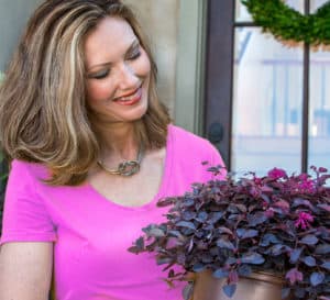 Woman in pink shirt holding Purple Daydream Loropetalum 2 gallon plant in brown plastic Southern Living Plant Collection pot