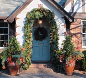 Blue door with wreath on it trimmed in holly