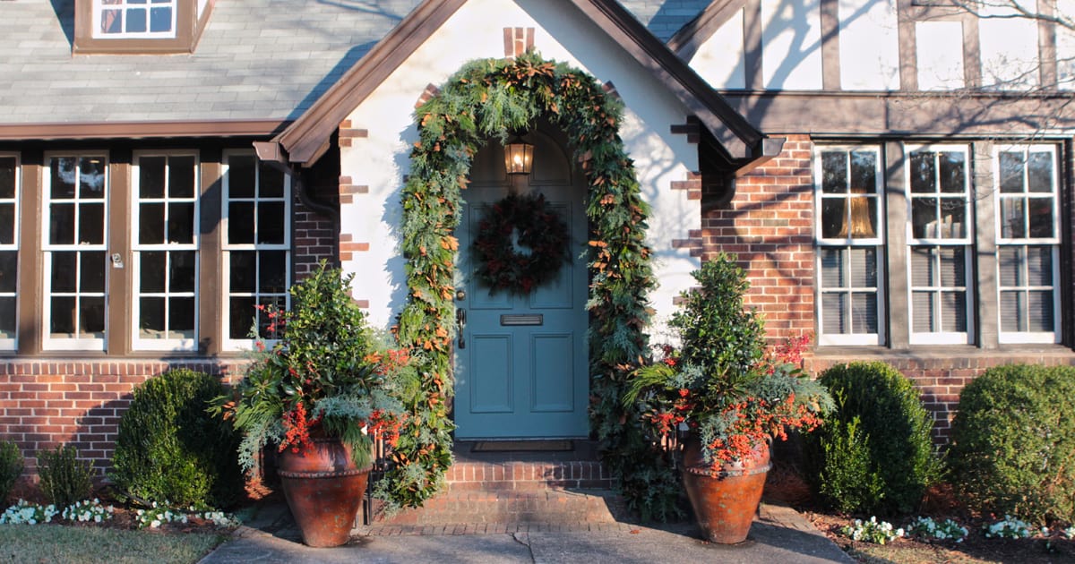 Blue door with wreath on it trimmed in holly