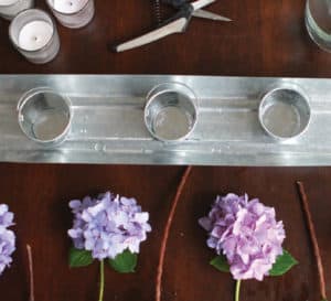 Wooden table with silver runner, silver candle holders and cut Dear Dolores Hydrangea blooms