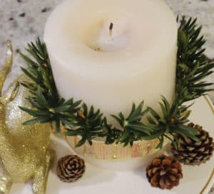 Trimming white candle with gold lacey ribbon with fern clippings