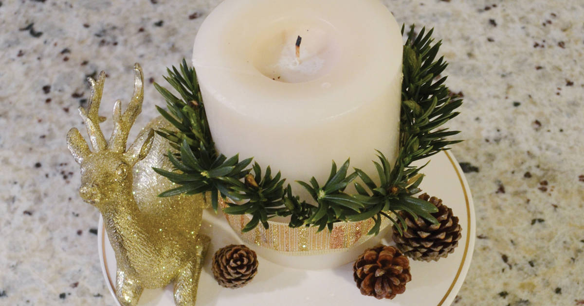 Trimming white candle with gold lacey ribbon with fern clippings