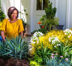 Woman in yellow shirt admiring her garden of Southern Living plants including Sunshine Ligustrum
