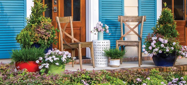 Cute front porch with two chairs filled with many potted and planted Southern Living Plants