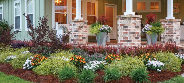 Mulitcolored flower bed in front yard with brick columns