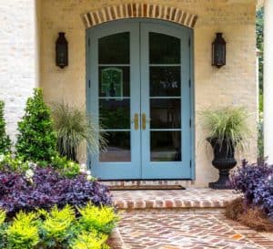 Brick patio with blue door framed with symmetrical planting of Southern Living plants in the garden and in container