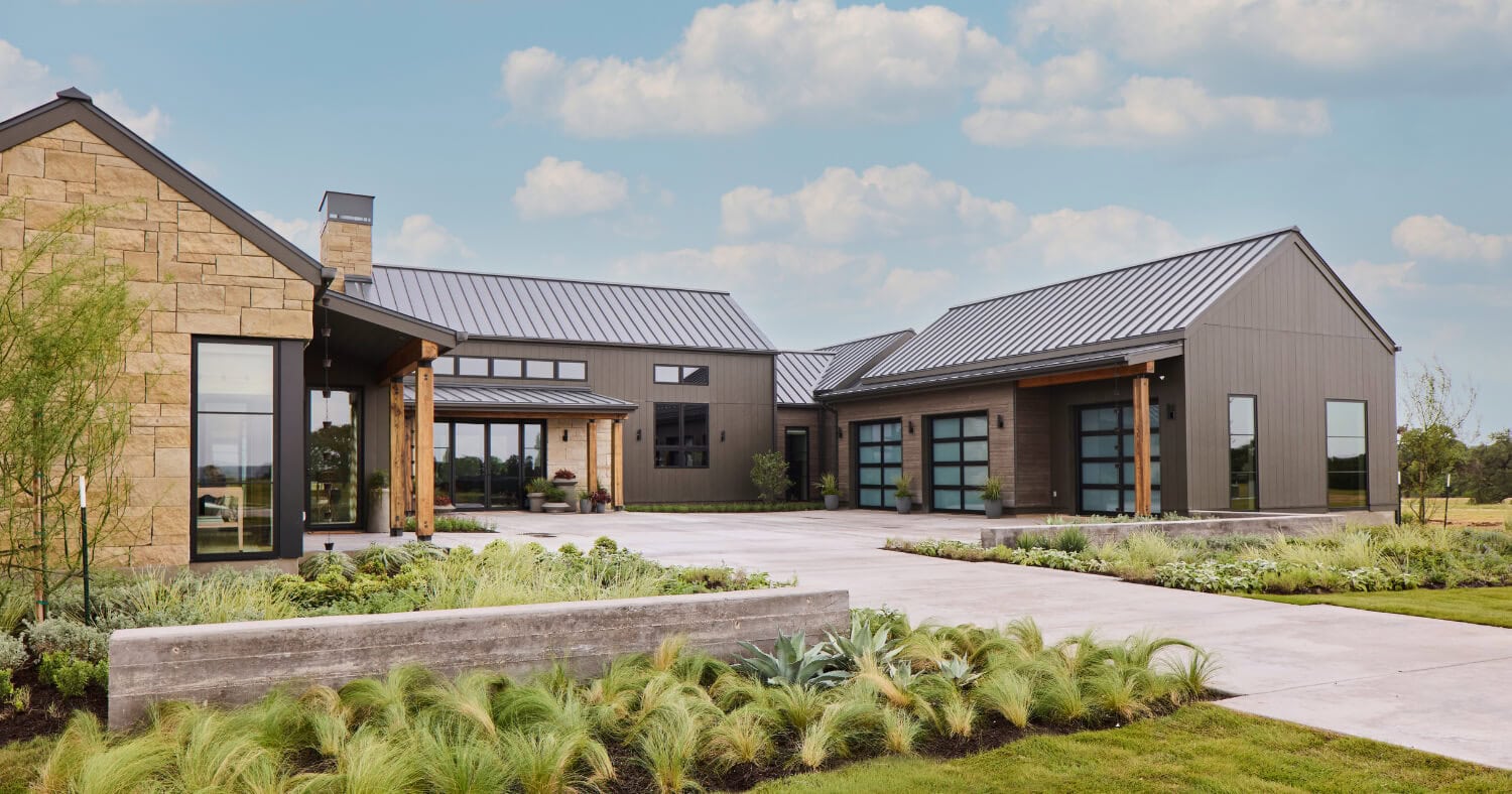 Front landscape of the 2026 Southern Living Idea House with layered shrubs, grasses, and evergreen foliage